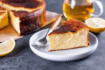 Piece of San Sebastian Basque Cheesecake on the plate with lemon and a cup of tea