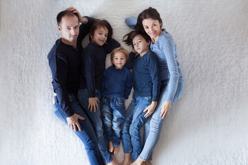 Happy family, mother, father and three boys, lying in bed, looking up, making heart shape, happiness