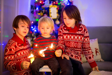 Waist up portrait of happy children celebrating New Year together and lighting sparklers