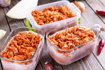 Frozen stewed cabbage in a container on a wooden background for freezing. Frozen food