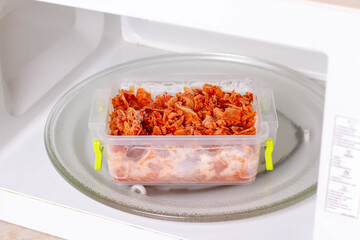 Frozen braised cabbage in a container in the microwave. Frozen food