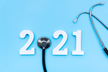 Flat lay of happy new year 2021. Number 2021 with stethoscope on blue background. health medical and new normal lifestyle concept. Copy space, top view