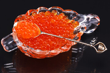 red caviar in a glass dish with a silver spoon