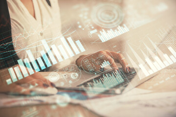 Double exposure of businesswoman hands typing on computer and forex graph hologram drawing. Financial analysis concept.