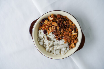 Homemade granola for breakfast. A bowl of milk shaved ice topped with granola, dried berries, cashew nut and walnut. (isolated)
