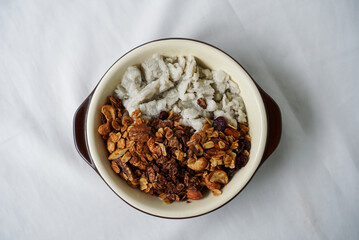 Homemade granola for breakfast. A bowl of milk shaved ice topped with granola, dried berries, cashew nut and walnut. (centre)