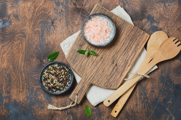 Wooden kitchen utensils and spices. Wooden spoons, cutting board, napkin and spices on a old wooden table. Top view