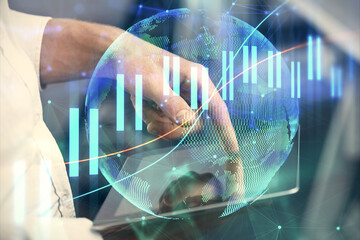 Double exposure of man's hands holding and using a digital device and forex graph drawing. Financial market concept.