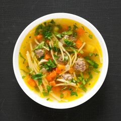 Homemade Sopa a La Minuta in a white bowl on a black surface, top view. Close-up.