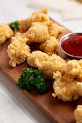 Homemade Popcorn Chicken on a rustic wooden board on a white wooden background, side view. Close-up.