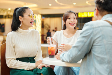 Beautiful young Asian women meeting with friends in cafe, drinking cocktails and joking around