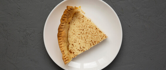 Piece of Homemade Sugar Cream Pie on a white plate on a gray background, top view. Flat lay, overhead, from above.