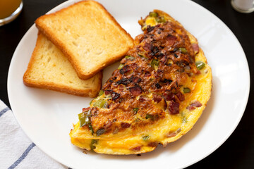 Homemade Denver Omelette on a white plate on a black background, low angle view. Close-up.