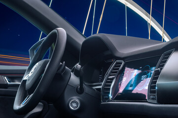 A modern car cockpit against the background of an illuminated bridge
