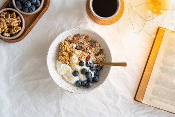 Top view book and Christmas healthy lifestyle breakfast with granola muesli and yogurt in bowl on...