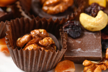 sweet food background for christmas or holiday decoration - chocolate candies, tangerines, nuts and dried fruits on white wood