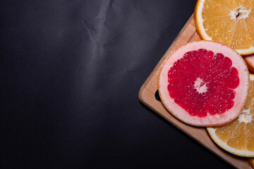 Oranges fruit on black wooden boards. Halves of juicy orange on black background. Orange fruit, citrus minimal concept. Top view, copy space