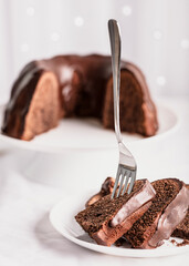 Dark chocolate cake covered with icing on a white stand. Selective focus.