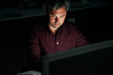 Portrait of a middle age focused businessman working late night in office - man working late for...