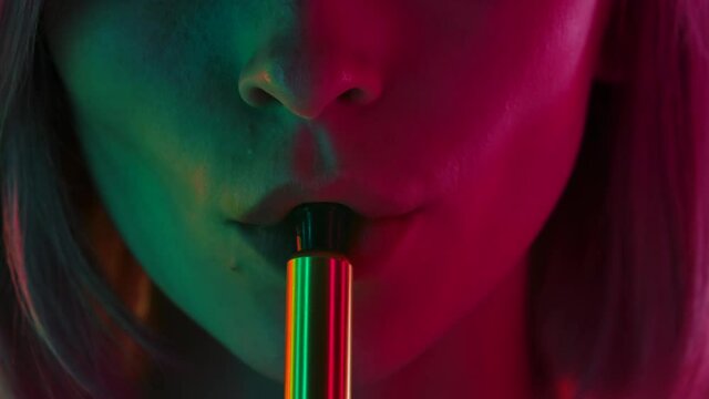 Portrait of a young stylish woman smokes hookah and blows white smoke directly into the camera. Close up macro portrait. Slow motion.