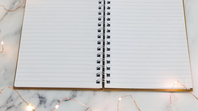 blank notebook with pages surrounded by fairy lights with copy space