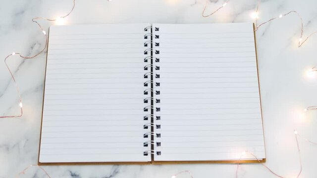 blank notebook with pages surrounded by fairy lights with copy space to add your text