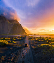 Schotterstraße bei Sonnenuntergang mit Berg Vestrahorn und Autofahren, Island