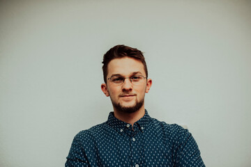 a portrait of a successful and happy caucasian businessman wearing glasses and a blue shirt