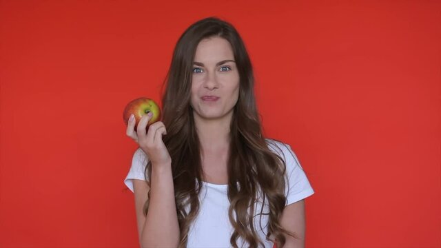 Woman eat apple. Girl bite apple fruit. Person beauty portrait. Dental health care. Female person enjoy apple in red studio. Healthy nutrition food. Female eating healthy fruit