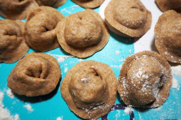 brown raw meat dumplings in the process of cooking from rye flour on a blue background side view