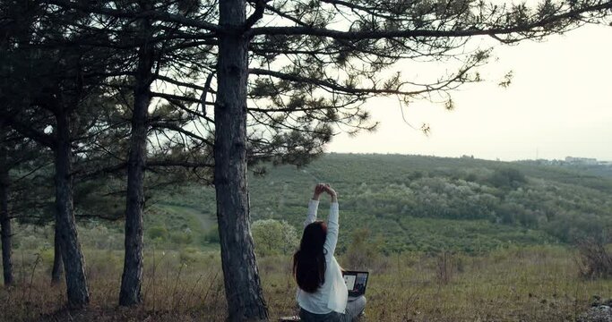 a girl lies down and holds her laptop in her arms in the park.