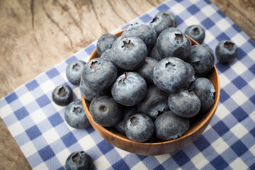 Fresh blueberries in wooden bowls on old wooden table background