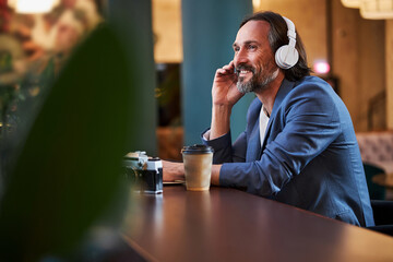 Joyful gentleman enjoying listening to music in his headphones