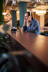 Travelling businessman unwinding at hotel lounge and listening to music