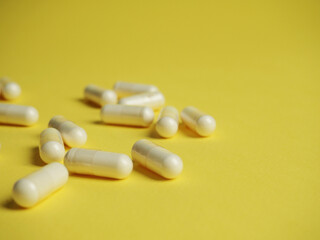 Fototapeta na wymiar a lot of different white tablets on a yellow background, the concept of health and medicine