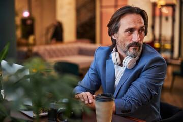Interested bearded gentleman waiting for somebody at hotel lounge