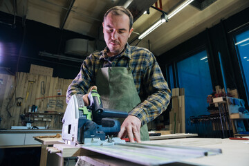 Wood craftsman makes a product for a private order, working on a machine for processing a wooden product