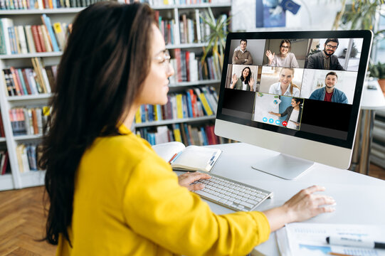 Online Learning. A Girl Student During Online Lesson Looks At The Monitor Screen On Which Other Students And A Teacher Teaching A Lesson