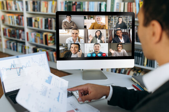 Multi ethnic business people gathered together in online video conference discuss financial strategy, colleagues have distant webcam conference with financial graphs
