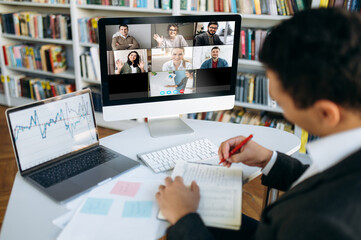Online video conference. Successful young adult businessman communicate with  business colleagues by video call using computer discussing about financial graphs and strategy