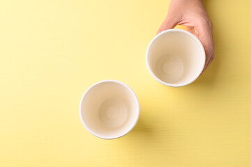 Hand holding biodegrable coffee cup on yellow background, Sustainable concept