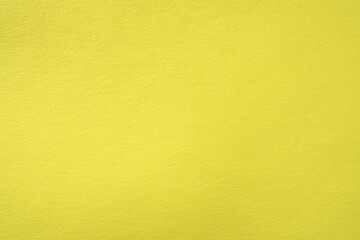 Paper background of pastel yellow color with fine texture.