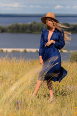 Girl in a blue dress walks in the field