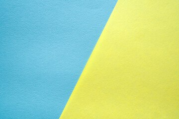 Paper texture background of pastel blue and yellow colors. Sheets of blank light blue and light yellow paper with fine texture devided  by a sloping border.