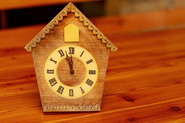 Retro cuckoo clock with Roman numerals on a wooden table.