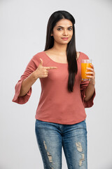 Pretty Indian young woman with orange juice on white.