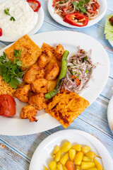 chicken shish kebab in a plate with appetizers. top wiev