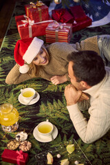Happy young couple drinking tea at home in Christmas time