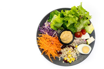 Healthy vegetable salad of fresh tomato, carrot, green oak, corn, Millet, egg , Purple cabbage and Salad dressing on black plate. Diet menu. vegan food concept.