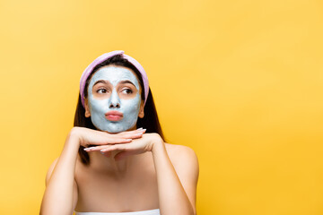 beautiful woman with clay mask on face isolated on yellow